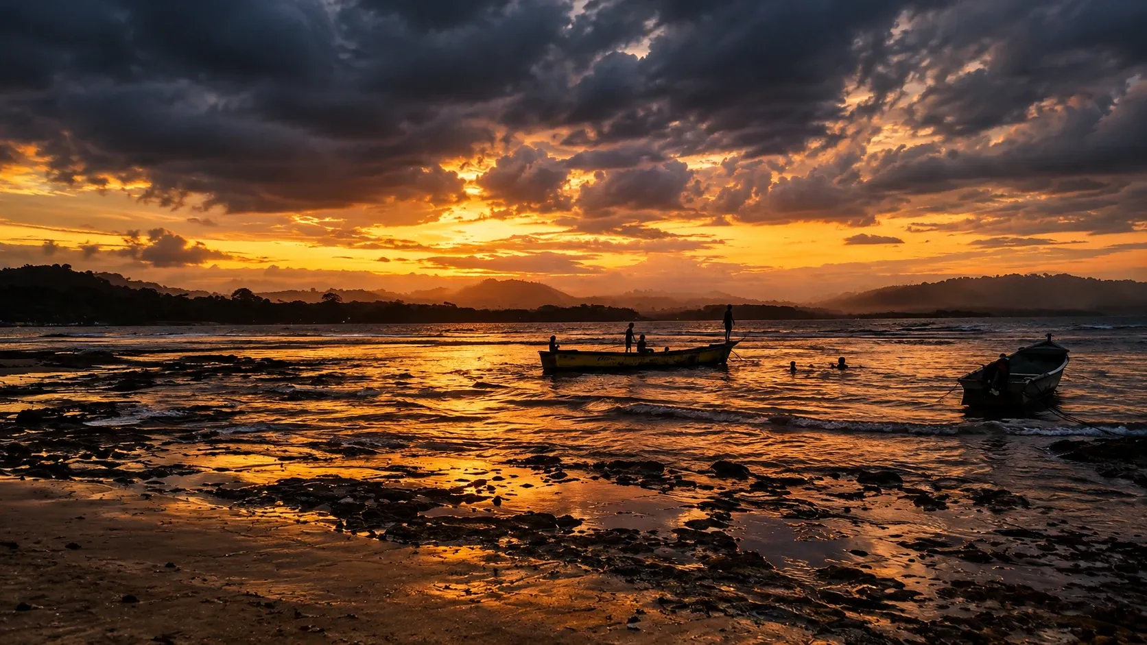 A dramatic orange sunset over the bay at Puerto Viejo, with a small boat and silhouettes