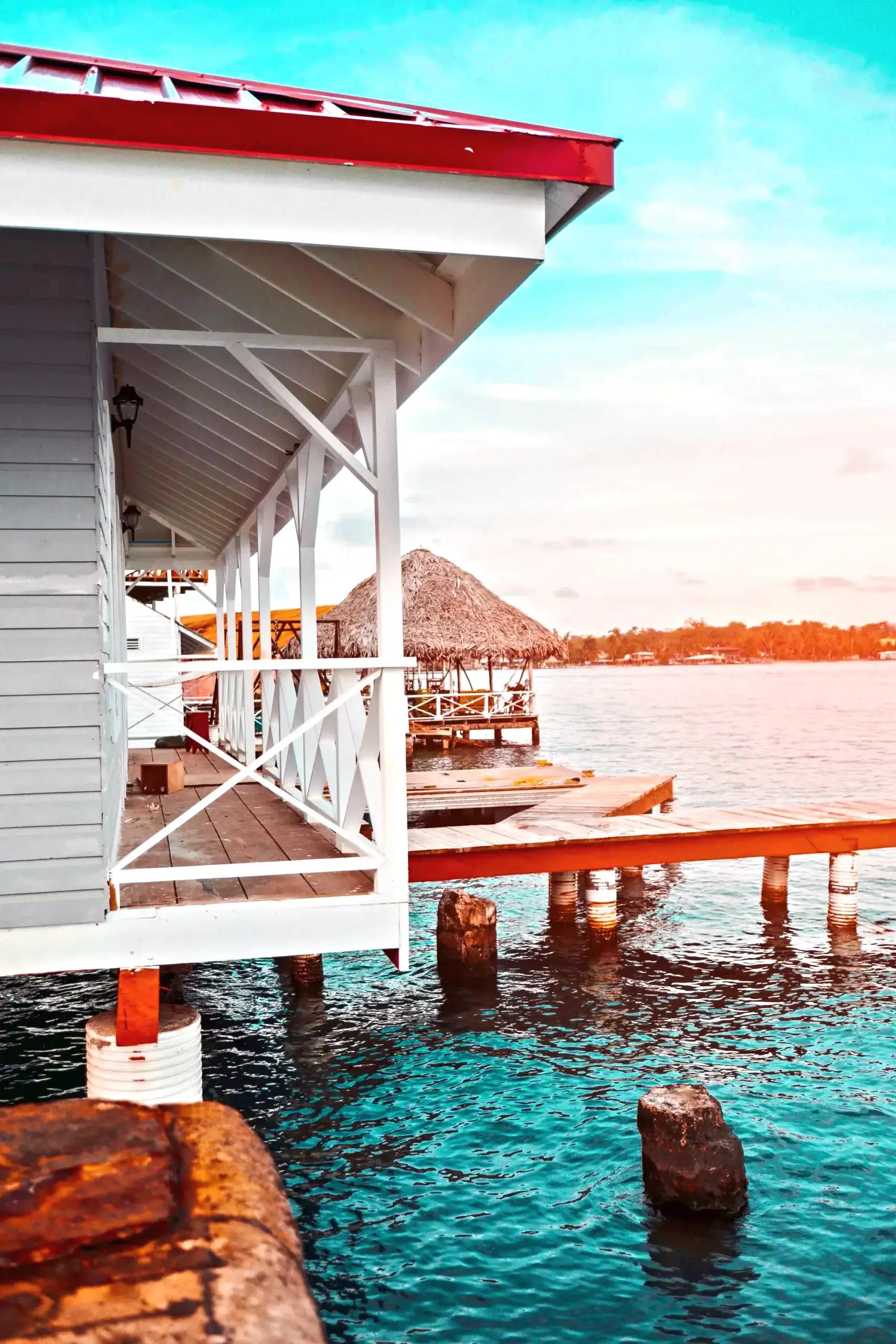 A white house on stilts over the water at sunset in Bocas del Toro, Panama