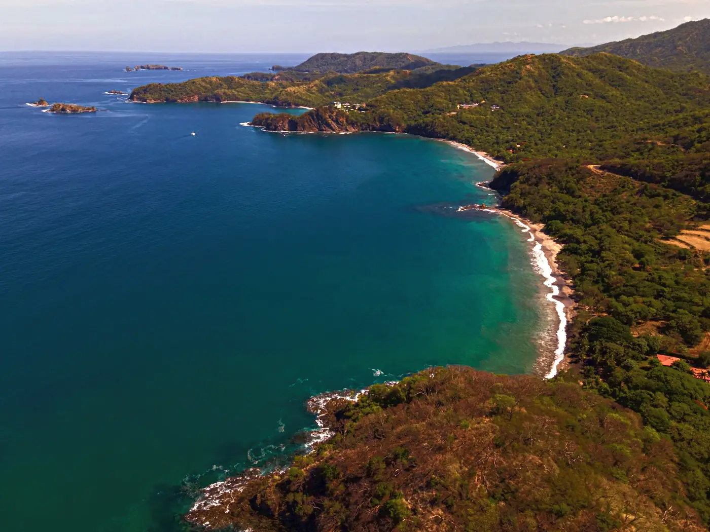 Aerial view of a forested headland and blue bay on the Guanacaste coast, Costa Rica