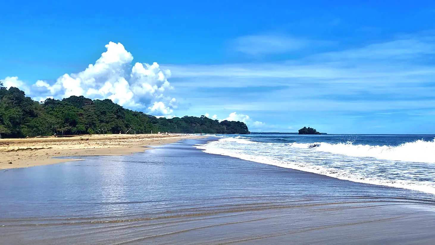 Wet sand and a deep blue sky at Playa Cocles