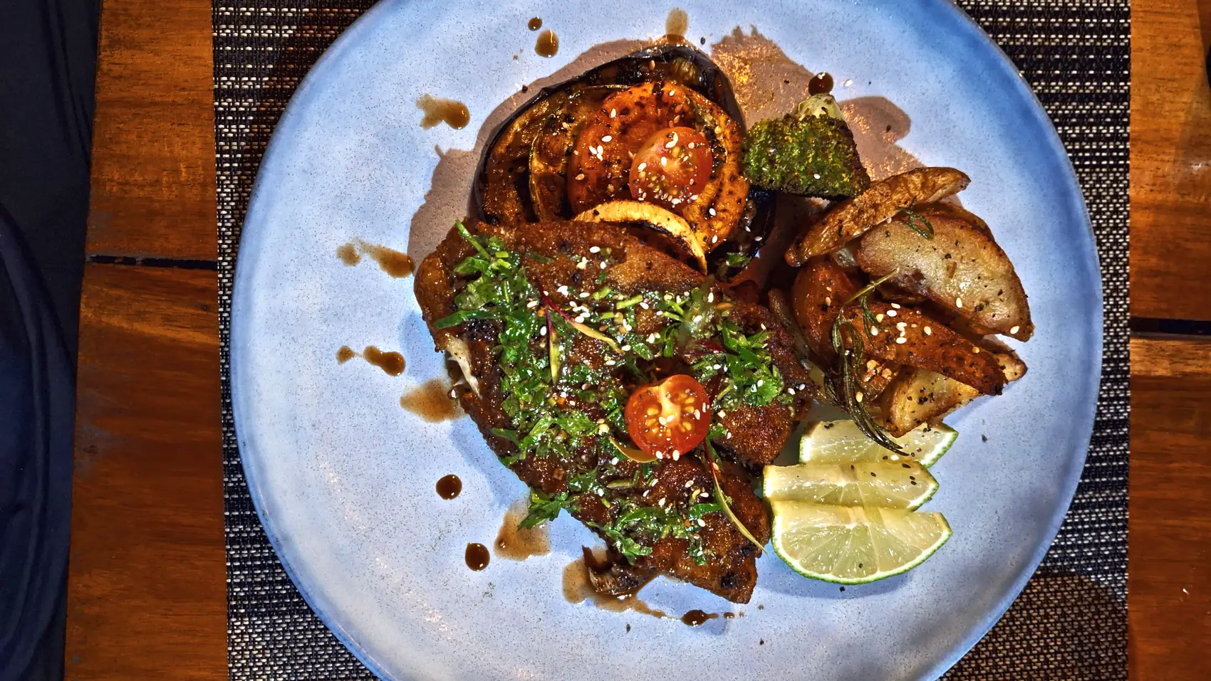 A plated main with herb sauce, lime and fried plantain